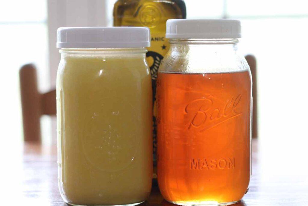 Two mason jars: one with rendered tallow, one with raw honey sitting on kitchen table