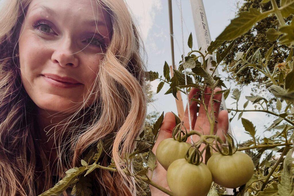 Kacie Barlow from Her Country Roots/Her Folk Roots showing off her tomatoes in her garden