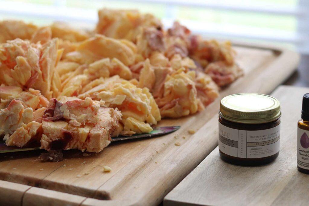 Raw beef fat, beef suet on cutting board beside a jar of tallow balm